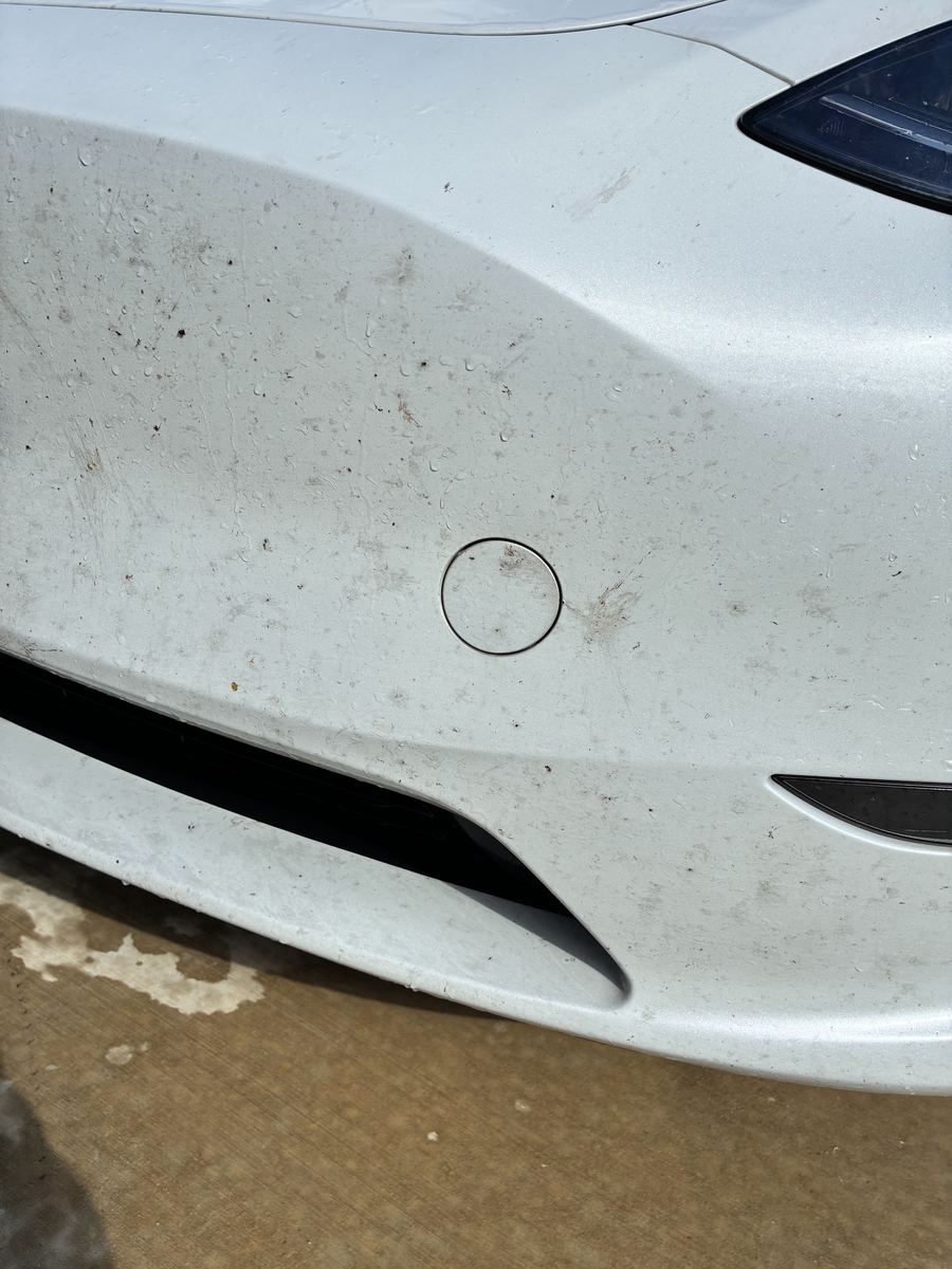 White SUV front bumper streaked with road grime before a Drip-N-Shine wash