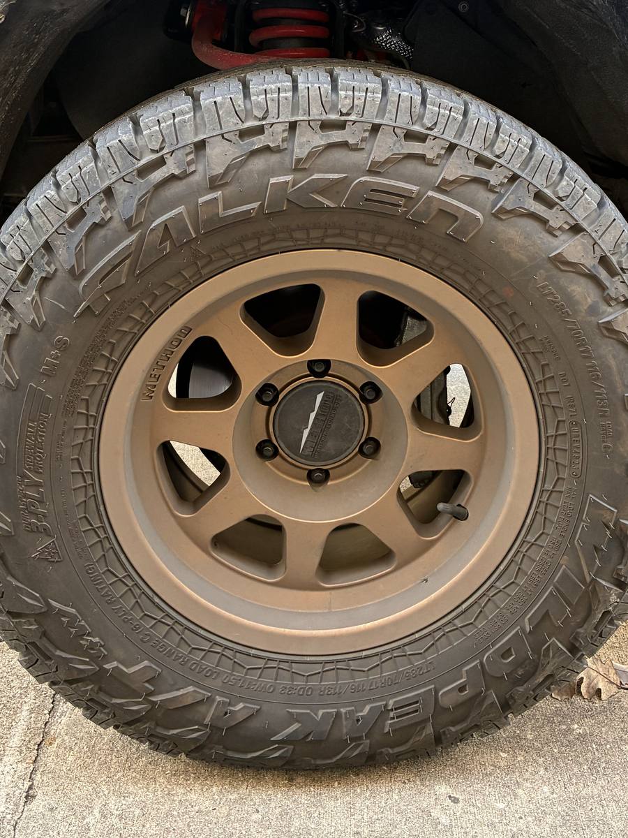 Bronze truck wheel and tire dulled with brake dust and Hill Country road grime before washing